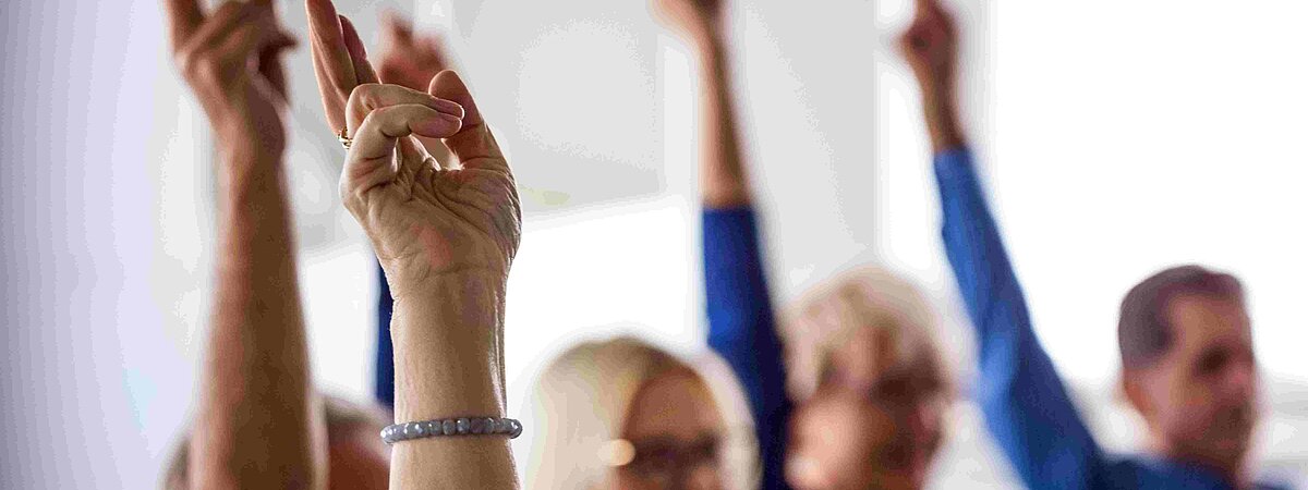 Menschen heben den Arm zur Abstimmung