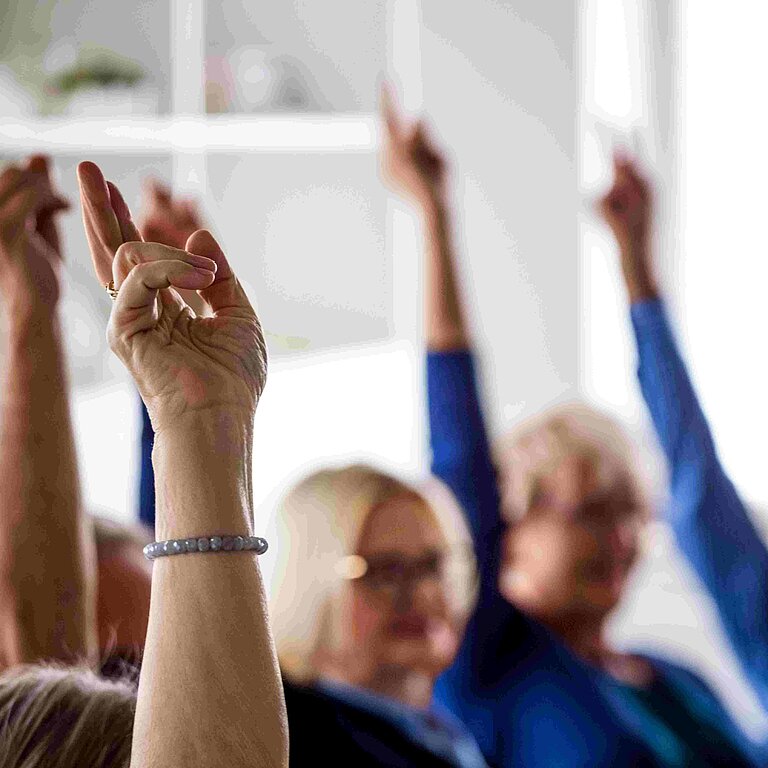 Menschen heben den Arm zur Abstimmung